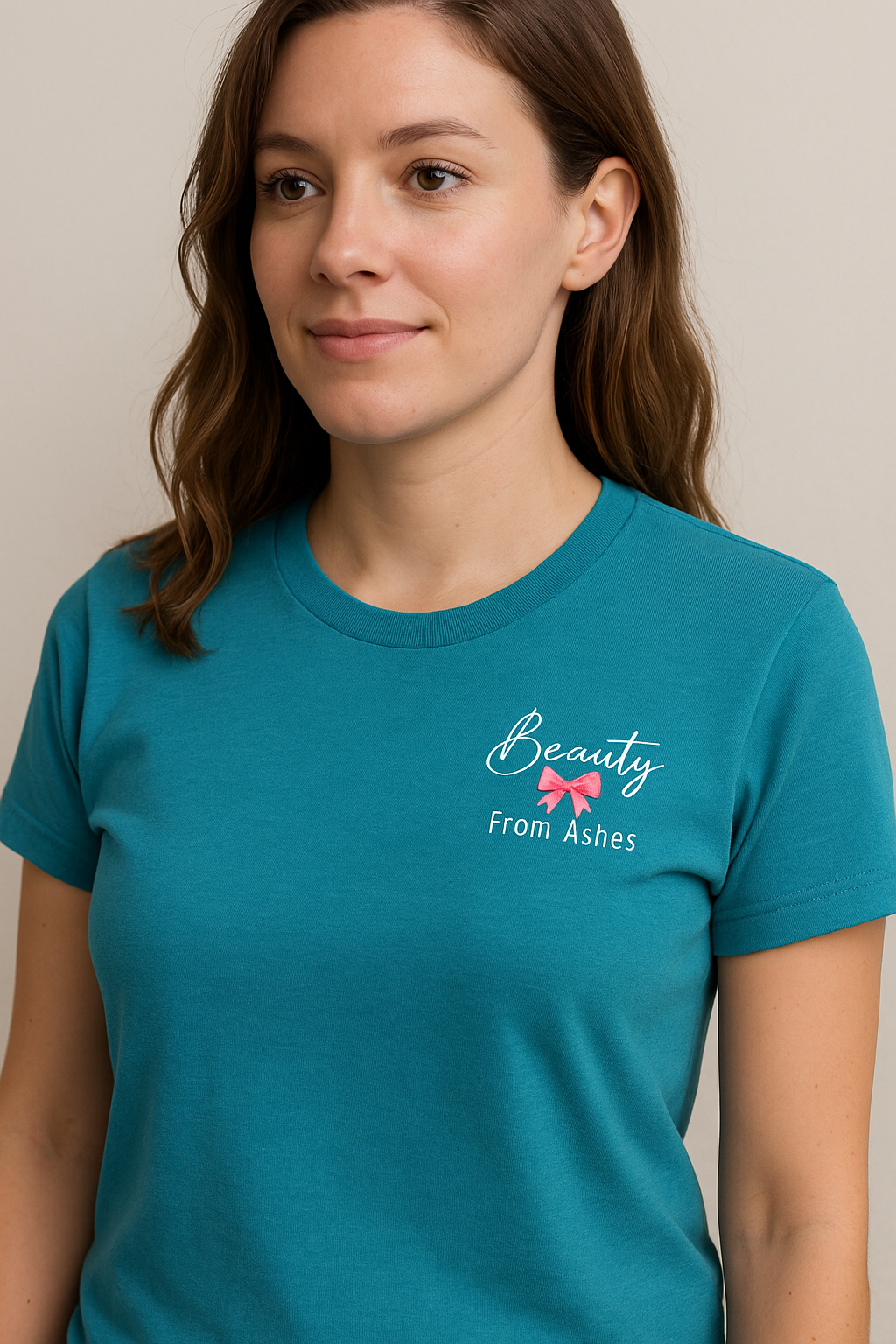 Woman wearing a teal t-shirt with 'Beauty From Ashes' text and logo.