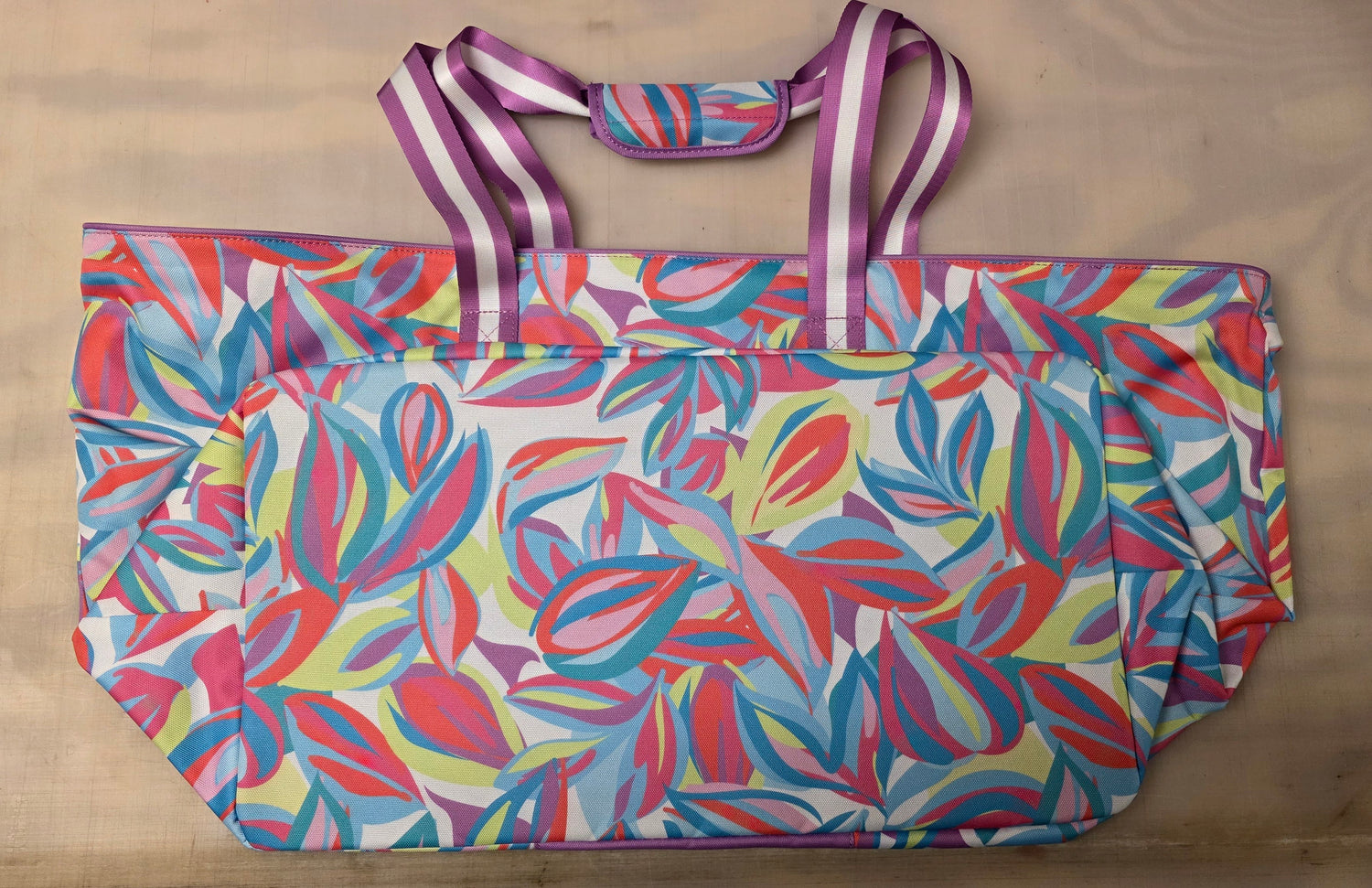 Colorful leaf patterned bag with a strap.
