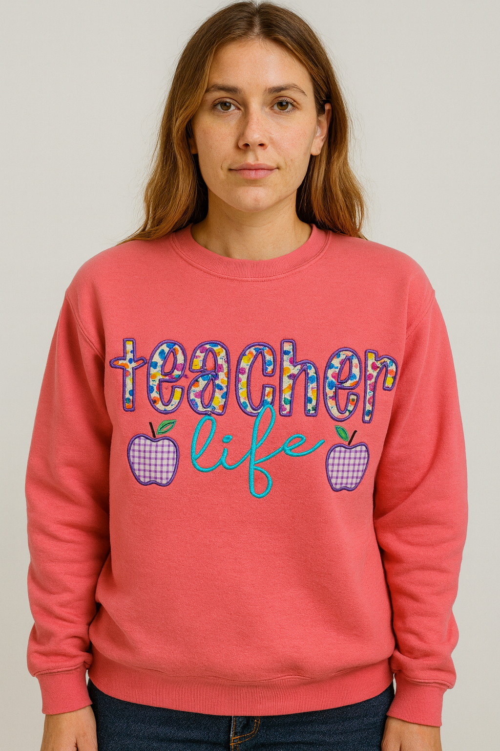 Person wearing a pink Lemonade sweatshirt with 'teacher life' text and apple graphics.