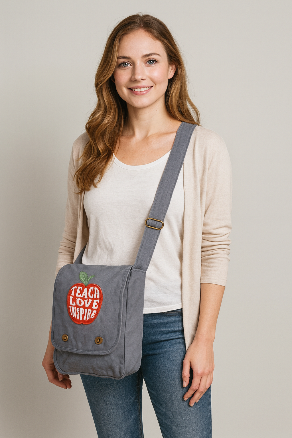 Woman wearing a gray crossbody bag with a visible design, standing against a plain background